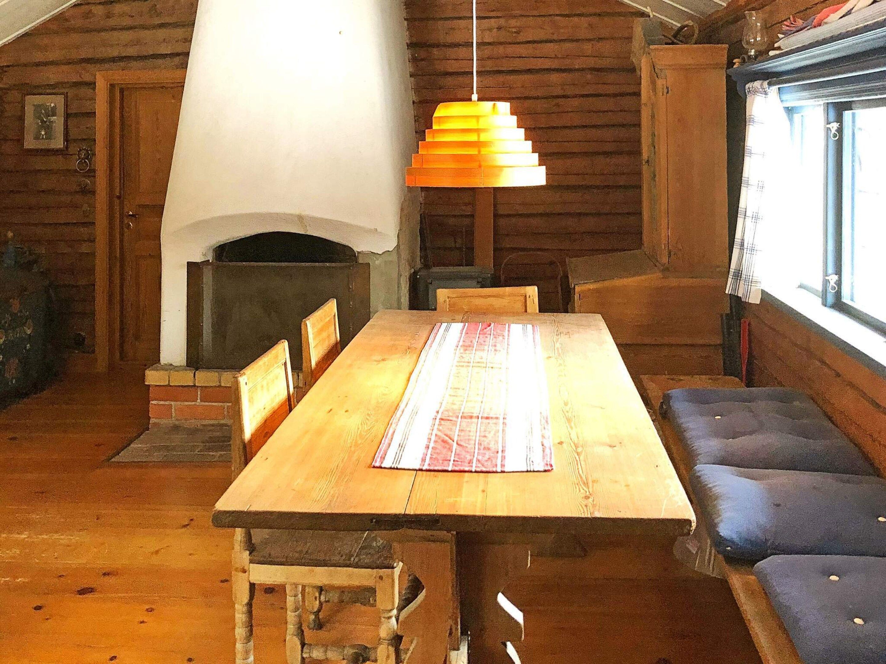 A wooden dining area with a fireplace, a bench, and a hanging light fixture.