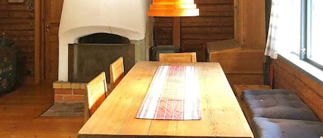 A wooden dining area with a fireplace, a bench, and a hanging light fixture.