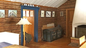 A rustic interior with wooden walls, a fireplace, and framed pictures on the wall.