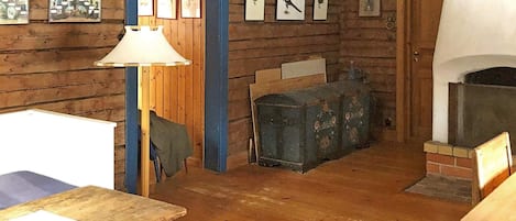 Un intérieur rustique avec des murs en bois, une cheminée et des tableaux encadrés accrochés au mur.