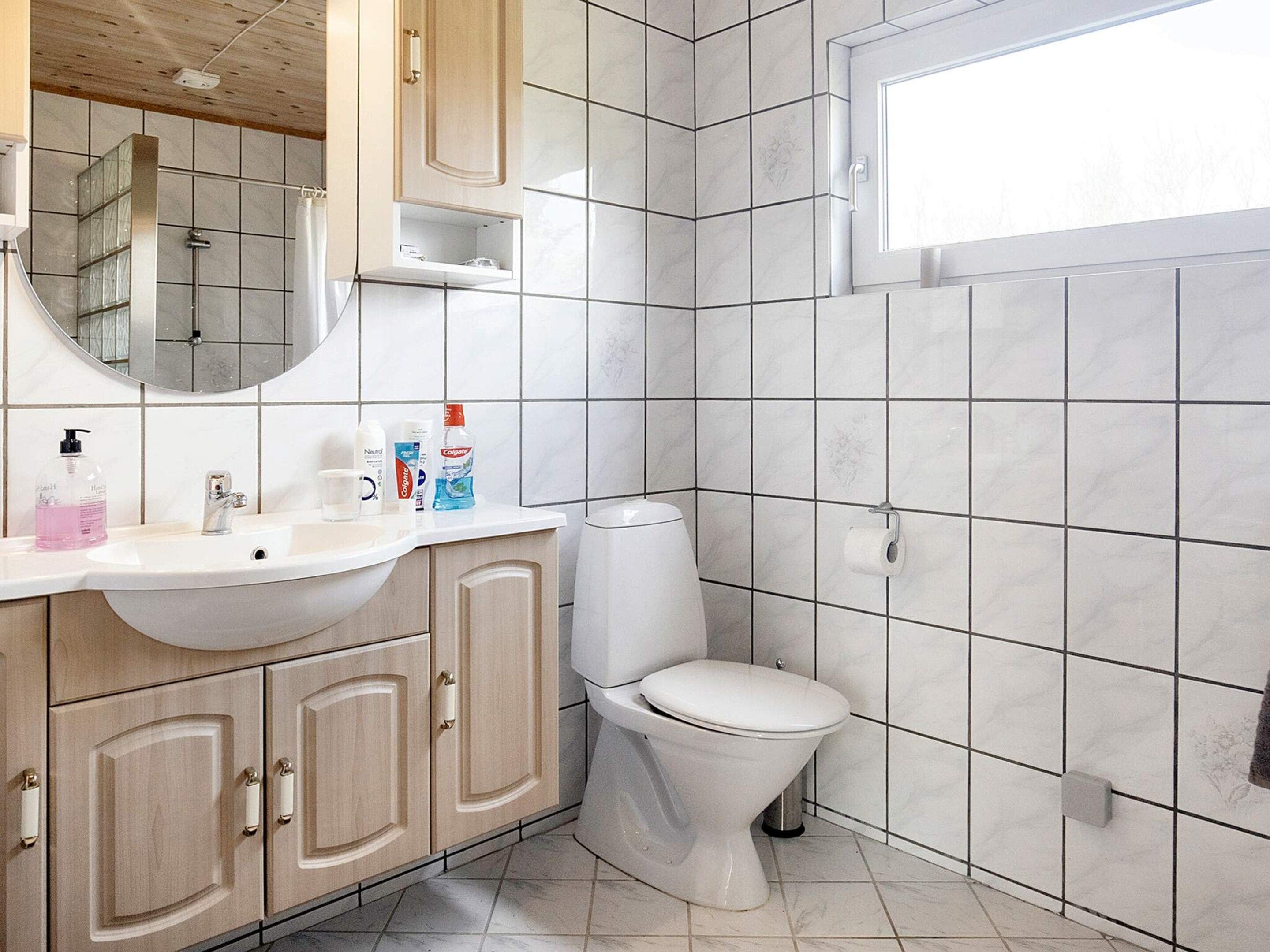 Ein Badezimmer mit weißem Waschbecken, Spiegel und Toilette.