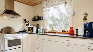 A kitchen with white cabinets, a stove, a window with curtains, and various kitchen items on the counter. - 5 Person Holiday Home in Asaa (Asaa)
