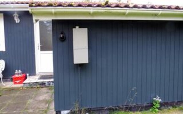 A single-story building with a dark exterior, a visible door, and a small window. - 5 Person Holiday Home in Asaa (Asaa)