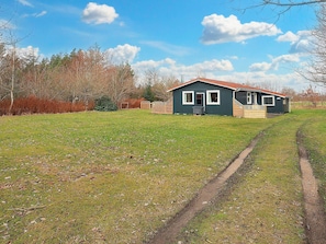 A single-story house with a red roof, a front porch, and a small front yard.