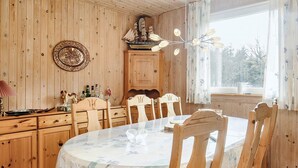 A wooden-paneled room with a round dining table, chairs, a cabinet, and a window with curtains. - 5 Person Holiday Home in Asaa (Asaa)