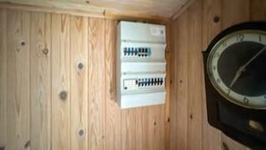 Paret de fusta amb un rellotge i un quadre elèctric.
