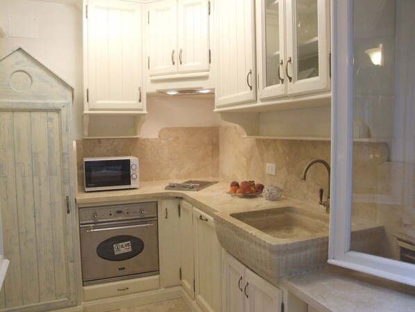 A kitchen with white cabinets, a microwave, an oven, and a sink.