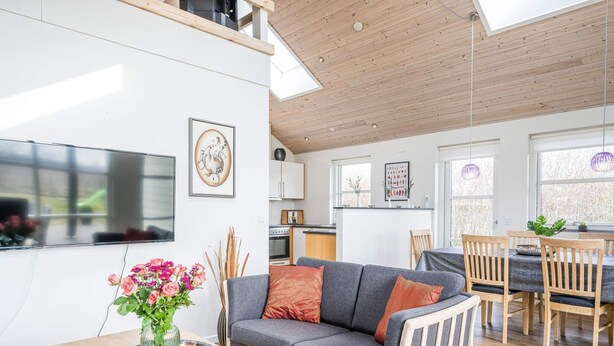 A modern living room with a grey sofa, wooden dining table, and a kitchen in the background. - 6 Person Holiday Home in Tarm (Hemmet)