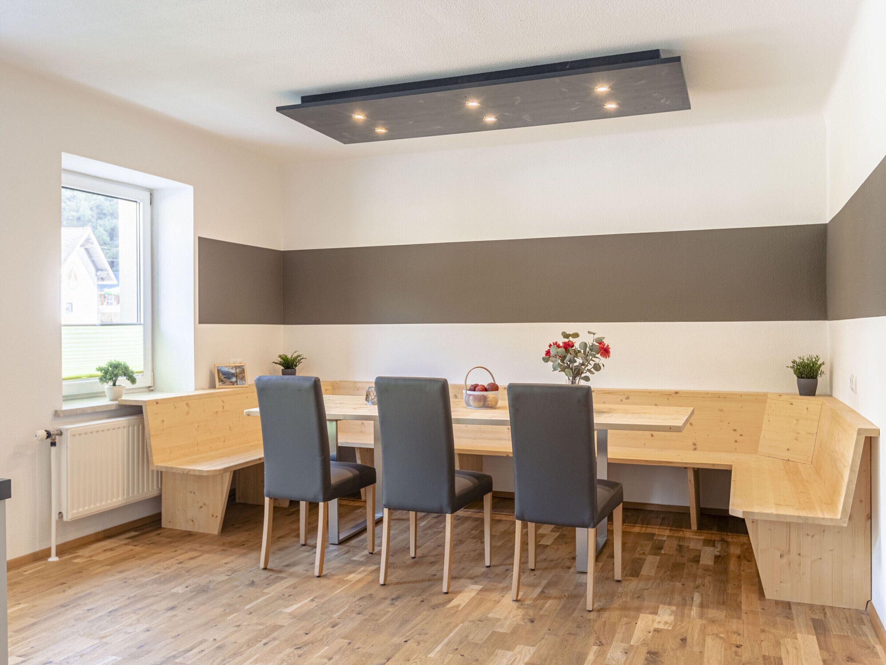 A modern kitchen with a wooden table, four chairs, and a built-in bench.