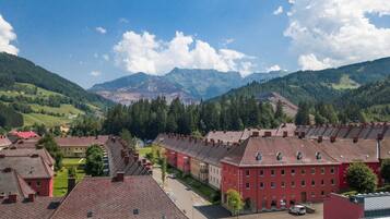 A town with red and yellow buildings, a central road, and mountains in the background.