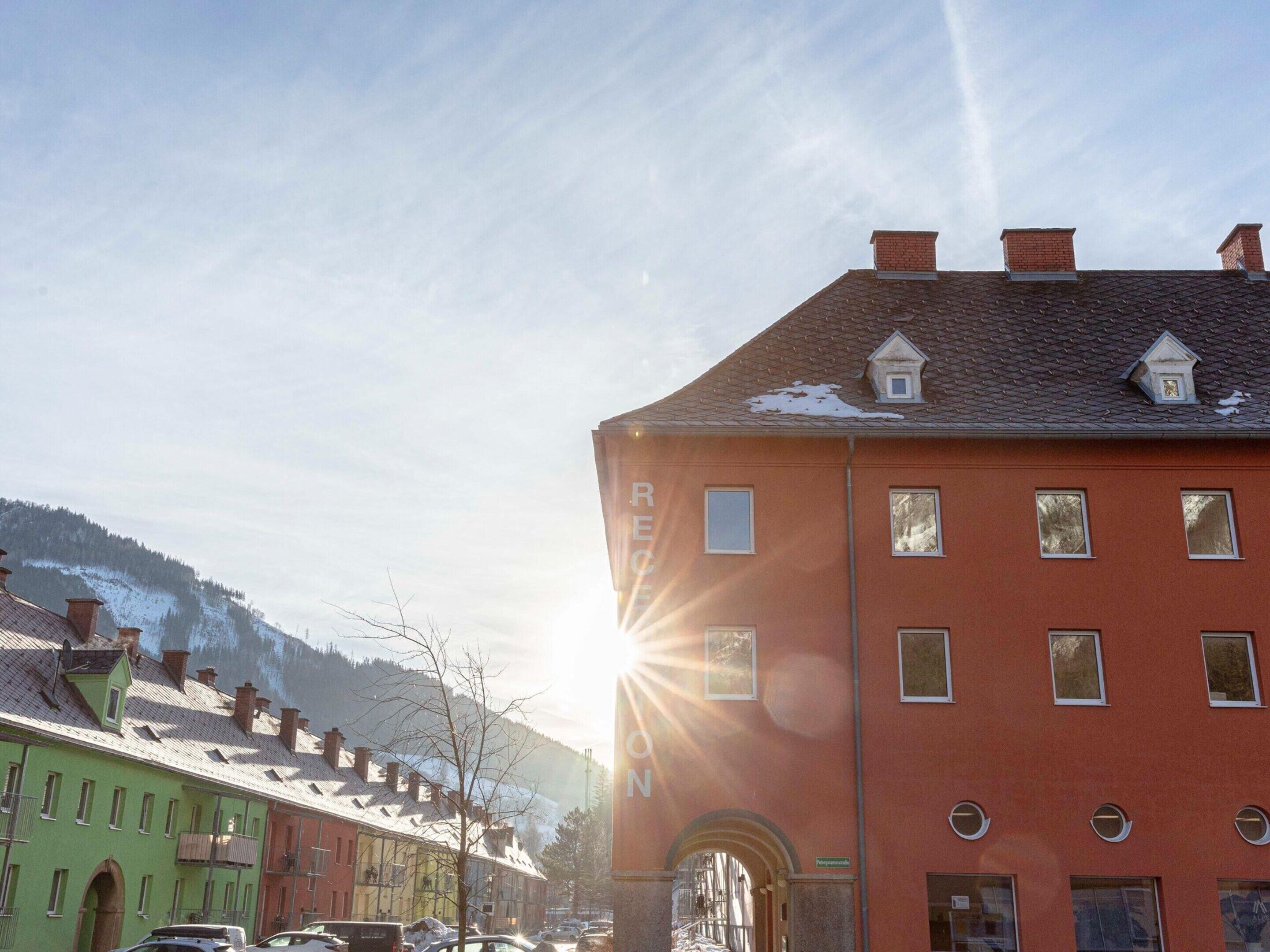 A street view with a red building, a green building, and a mountain in the background.
