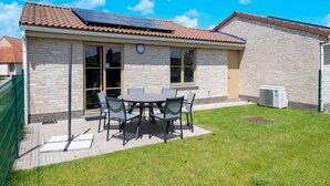 A building with a tiled roof, a brick exterior, and a patio area with a table and chairs. - Holiday Home in Koksijde With Private Garden (Koksijde)