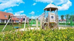 A playground with a climbing structure, swings, and a slide. - Holiday Home in Koksijde With Private Garden (Koksijde)