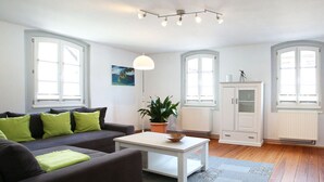 A modern living room with a sofa, coffee table, and potted plant. - Holiday Apartment Faller-greiner (Bad Bergzabern)