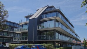A modern multi-story building with large glass windows and balconies. - Apartment Nieuwpoort Near Beach (Nieuwpoort)