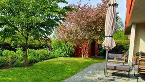 Un giardino curato con un vialetto sterrato, un tavolo in legno con un libro e sedute all'aperto.