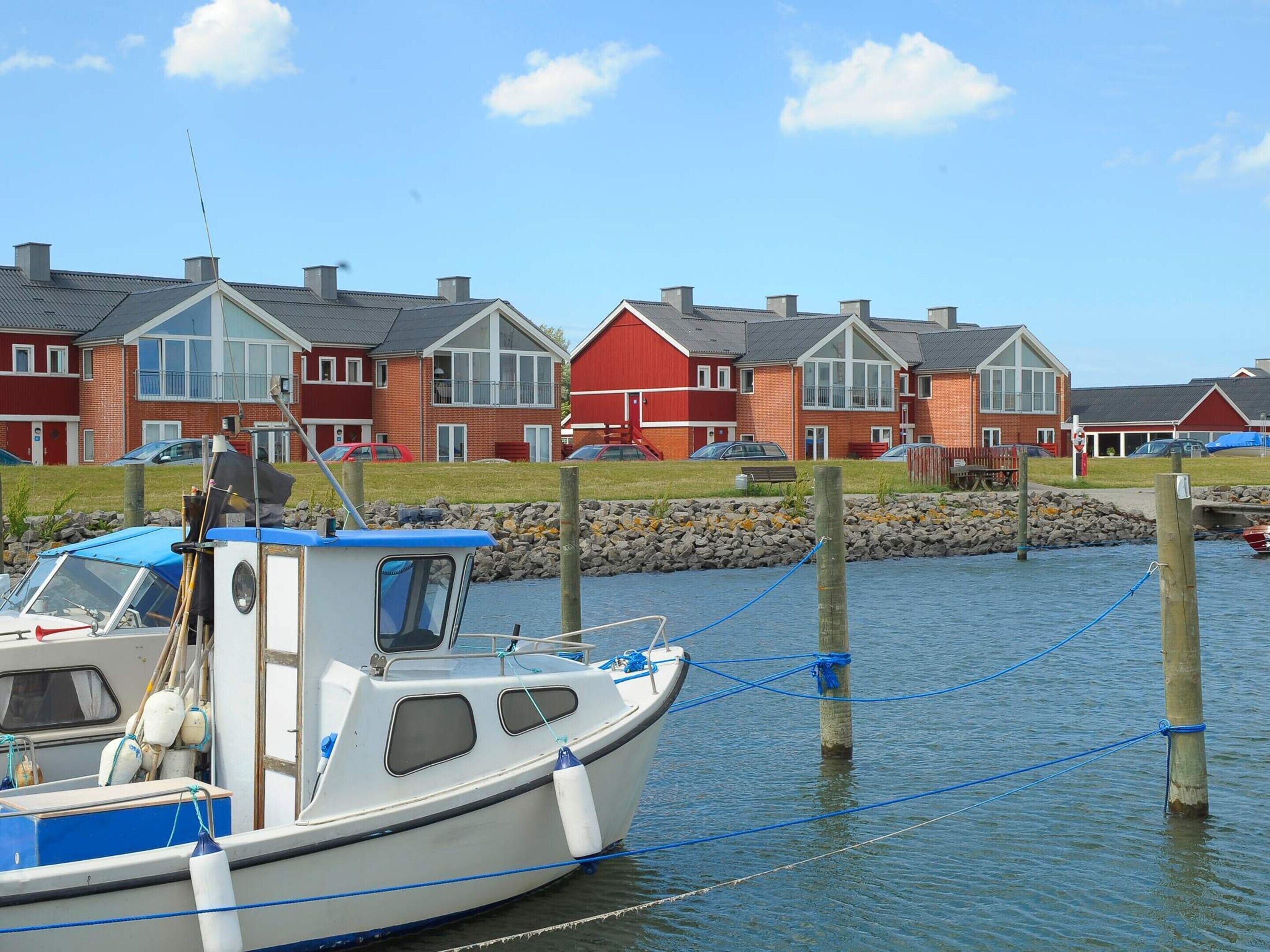 A row of red and white houses by a calm water body with a boat docked nearby.