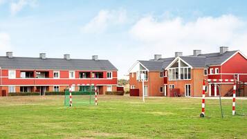 Zona residencial con dos casas de ladrillo rojo, un campo deportivo y un arco de fútbol.
