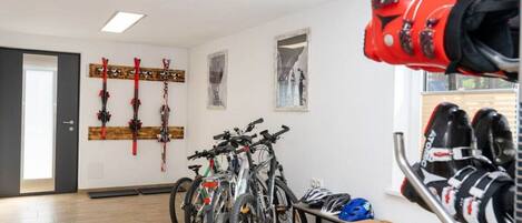Una habitación con bicicletas, cascos y esquíes en portaequipajes.