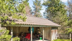 A rustic wooden cabin with a tiled roof, a covered porch, and a bicycle parked outside.
