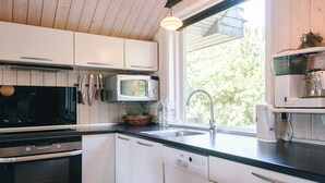 A modern kitchen with white cabinets, a microwave, a sink, and a coffee maker.