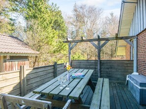 An outdoor wooden deck with picnic tables and a barbecue grill. - 4 Star Holiday Home in Blavand (Blavand)
