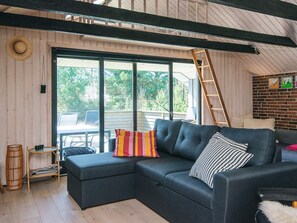 A modern living room with a sectional sofa, a dining table, and a view of the outdoors. - 4 Star Holiday Home in Blavand (Blavand)