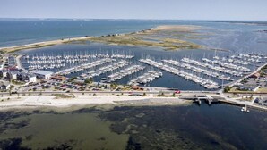 An aerial view of a marina with numerous boats docked, a sandy beach, and a clear view of the water. - Houseboat Grey Seal Comfortable Vacation Home (Heiligenhafen)