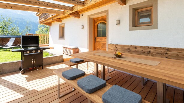 An outdoor patio with a wooden table, benches, and a grill. - Renovated Farmhouse Stoanerbauer With View (Bramberg am Wildkogel)