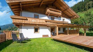 A two-story chalet with a wooden balcony and a deck, surrounded by a lush green landscape. - Renovated Farmhouse Stoanerbauer With View (Bramberg am Wildkogel)