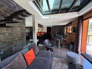 A modern interior with a sofa, ottoman, and dining area.