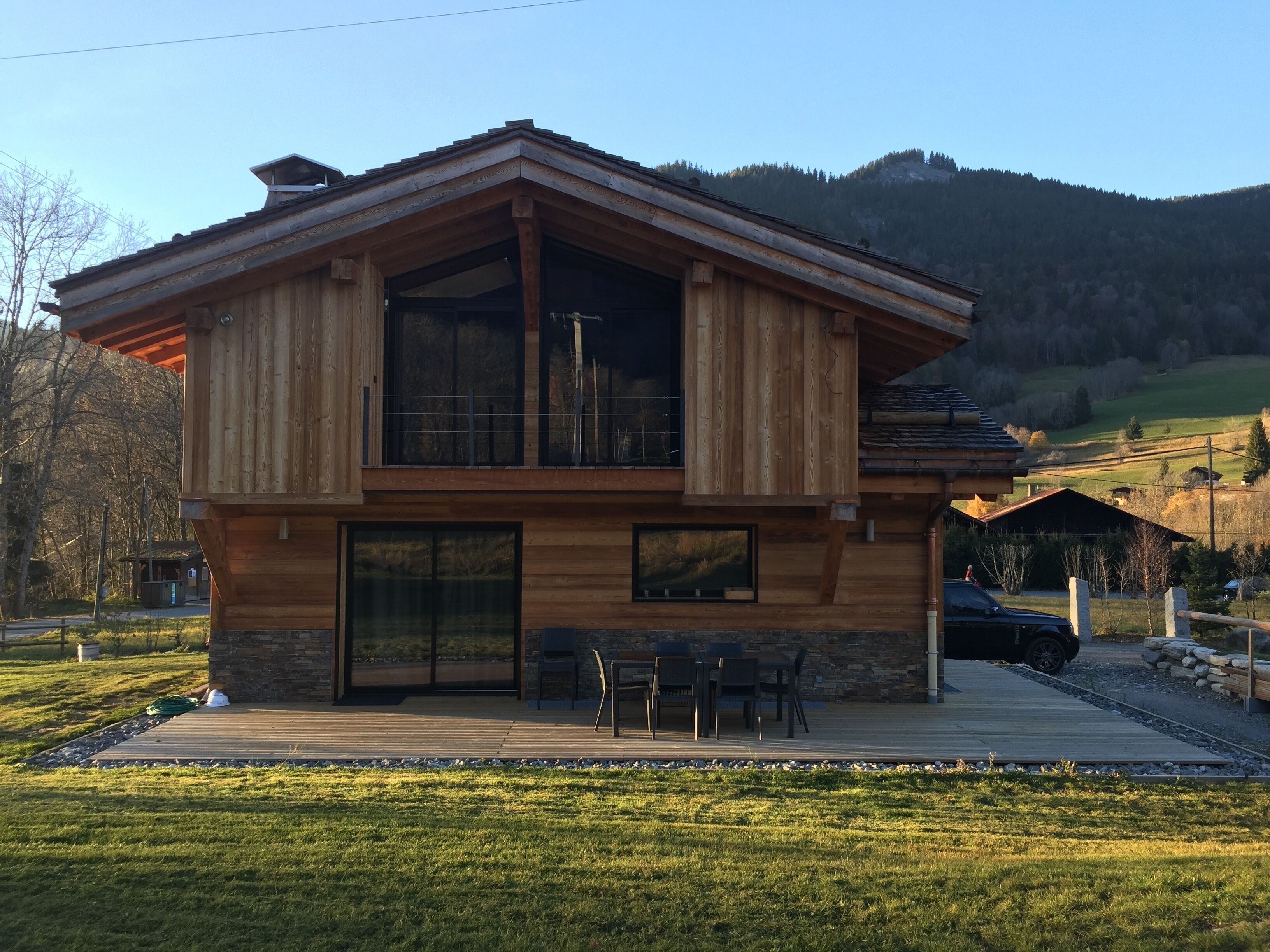A two-story wooden cabin with large windows and a deck.