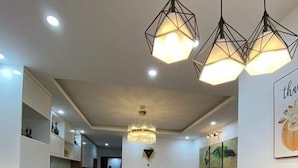 A modern dining area with a marble table set for four, a brown sofa, and pendant lighting. - Happy Home (Quan Trieu)