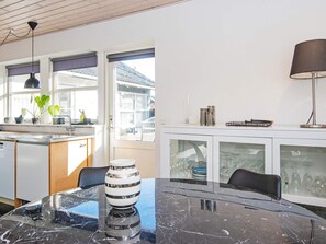 A modern kitchen with a marble countertop, a dining table, and a cabinet with glass doors. - 4 Person Holiday Home in Ebeltoft (Ebeltoft)