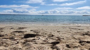 A beach with calm water, distant boats, and a clear sky. - 4 Person Holiday Home in Ebeltoft (Ebeltoft)