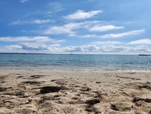 A beach with calm water, distant boats, and a clear sky. - 4 Person Holiday Home in Ebeltoft (Ebeltoft)