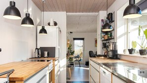 A modern kitchen with wooden countertops, black pendant lights, and a view into the dining area. - 4 Person Holiday Home in Ebeltoft (Ebeltoft)