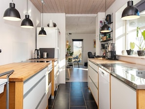 A modern kitchen with wooden countertops, black pendant lights, and a view into the dining area. - 4 Person Holiday Home in Ebeltoft (Ebeltoft)