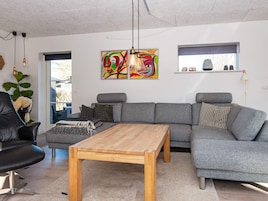 A modern living room with a grey sectional sofa, a wooden coffee table, and a colorful abstract painting.