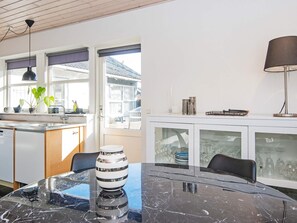 A modern kitchen with a dining area, featuring a marble table, a kitchen island, and a view through the glass doors. - 4 Person Holiday Home in Ebeltoft (Ebeltoft)