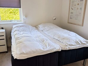 A single bed with white bedding in a room with a window, a wall-mounted light, and a framed picture. - 4 Person Holiday Home in Ebeltoft (Ebeltoft)