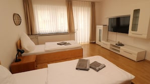 Ein Hotelzimmer mit Bett, Fernseher, Schreibtisch und einem fenster mit Vorhängen.