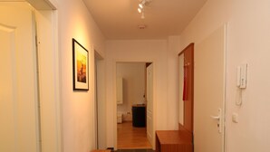 Ein Korridor mit einer hölzernen Bank, einem gerahmten Bild an der Wand und einem Telefon.