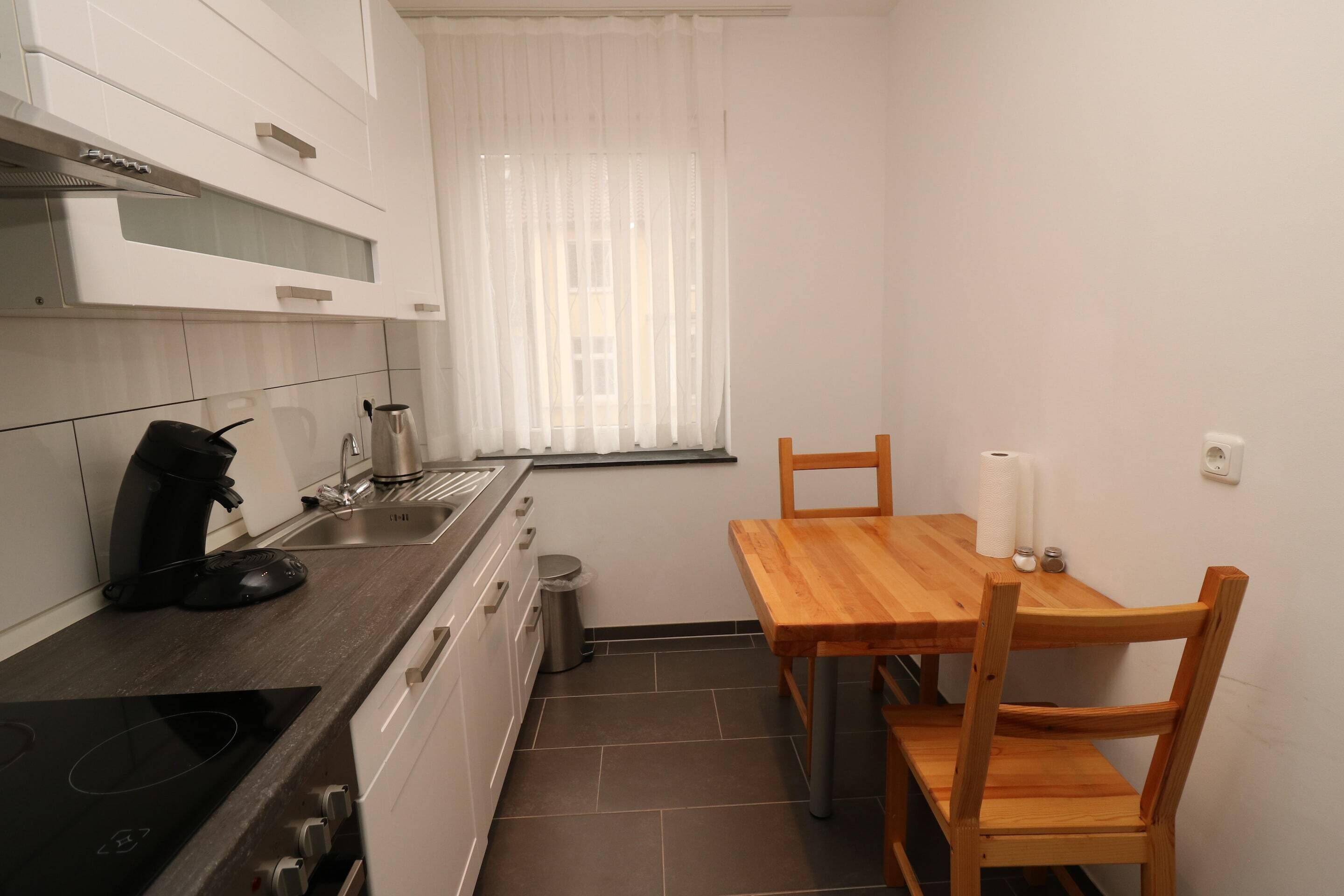 A compact kitchen with a stove, sink, and a dining table with chairs.