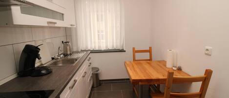 A compact kitchen with a stove, sink, and a dining table with chairs.