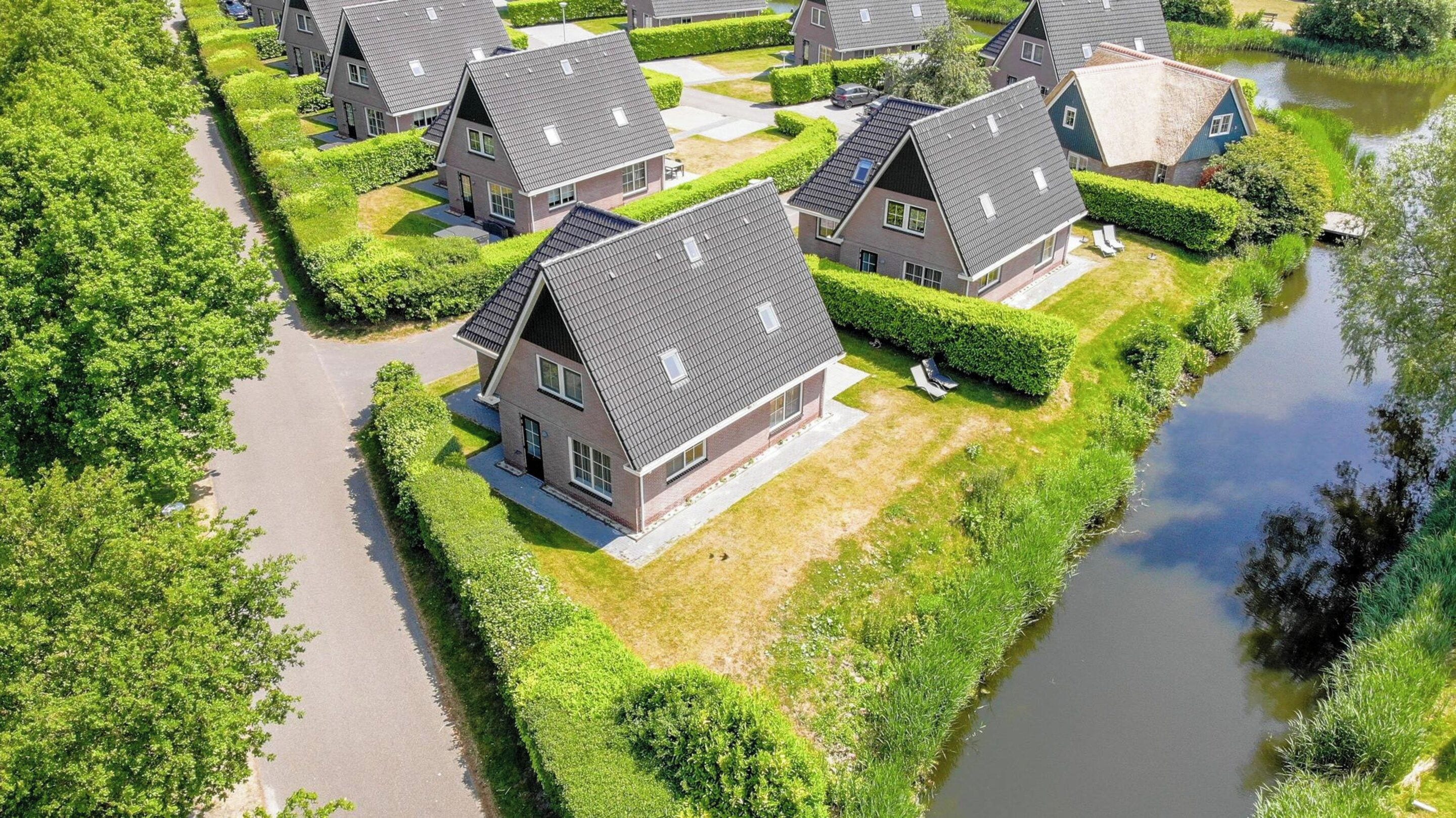 Et boligområde med flere huse, en smal kanal og velplejede grønne områder.