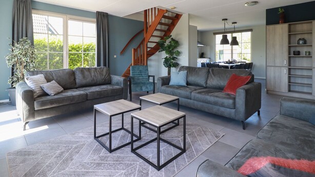 A modern living room with two grey sofas, a wooden coffee table, and a staircase leading to an upper level. - Villa With Jacuzzi and Sauna in Makkum (Makkum)