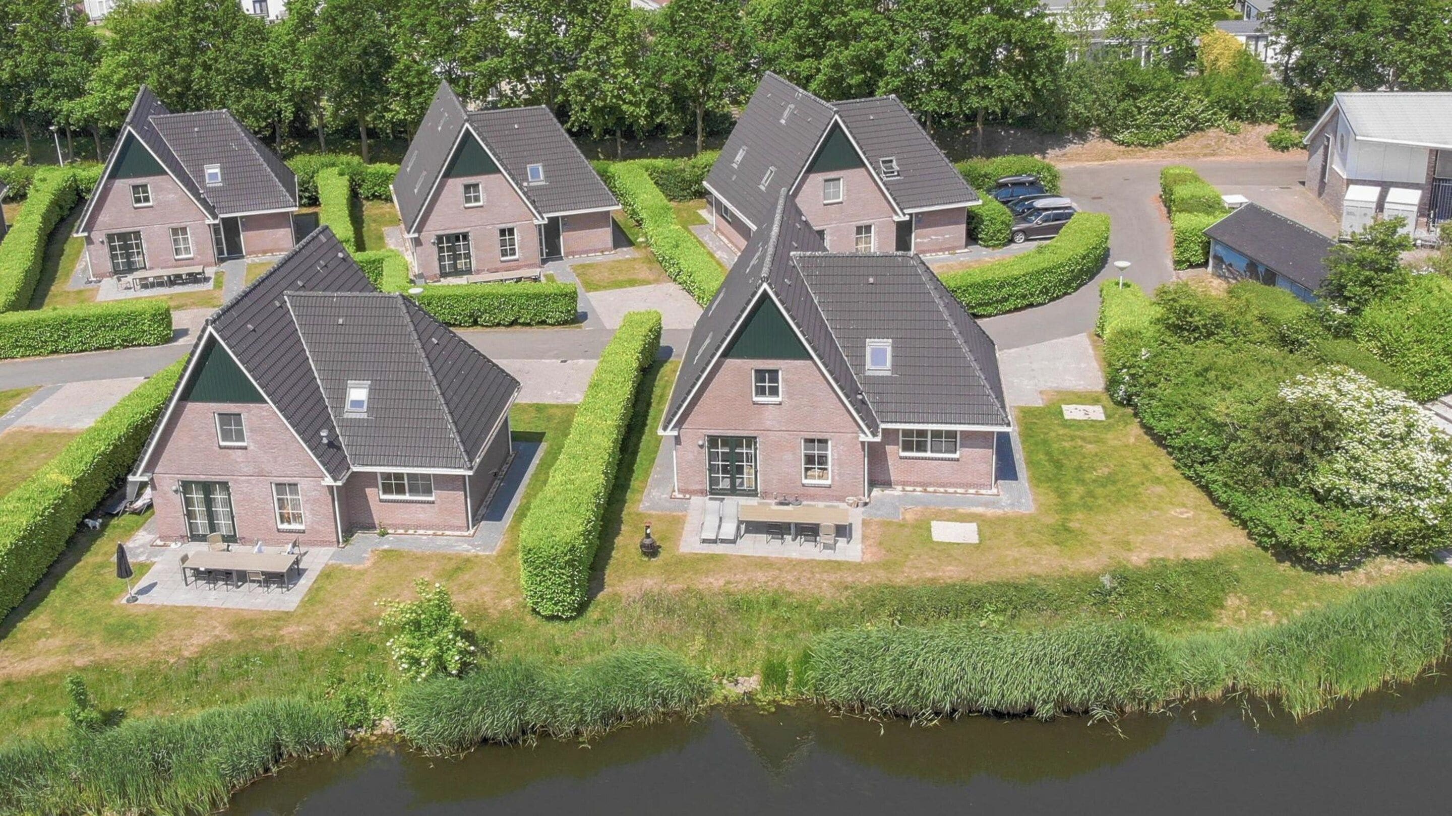 Un barrio residencial con varias casas, un pequeño estanque y céspedes cuidados.