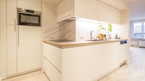 Una cocina moderna con horno empotrado, salpicadero de mármol y una isla grande con lavamanos y encimera.