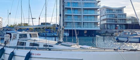 A marina with boats docked, a building with multiple floors, and a clear sky.
